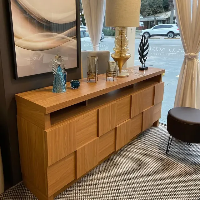 Aparador de madeira com abajur e objetos de decoração